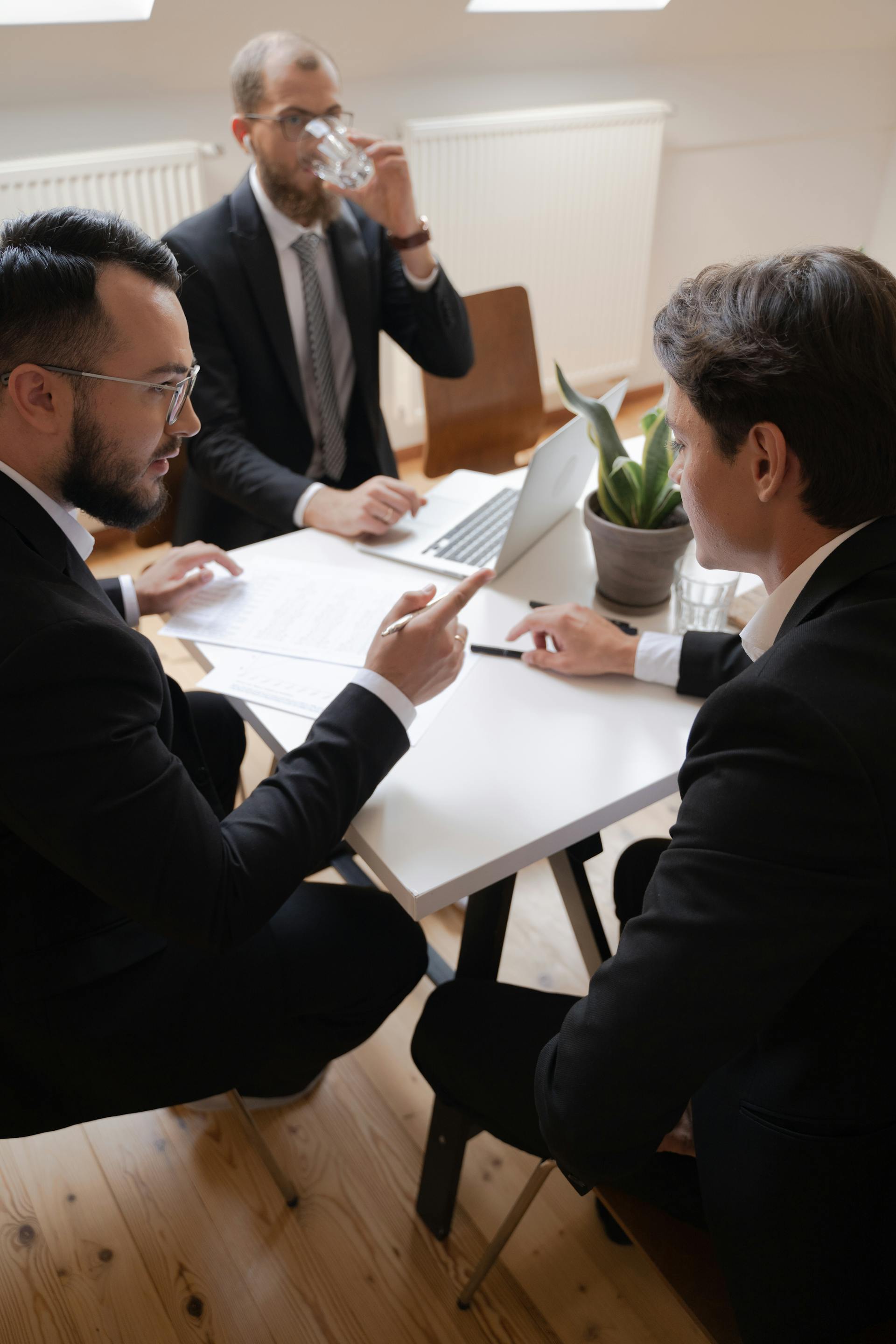 Drei Geschäftsleute führen während eines formellen Meetings in einer Büroumgebung eine Diskussion.